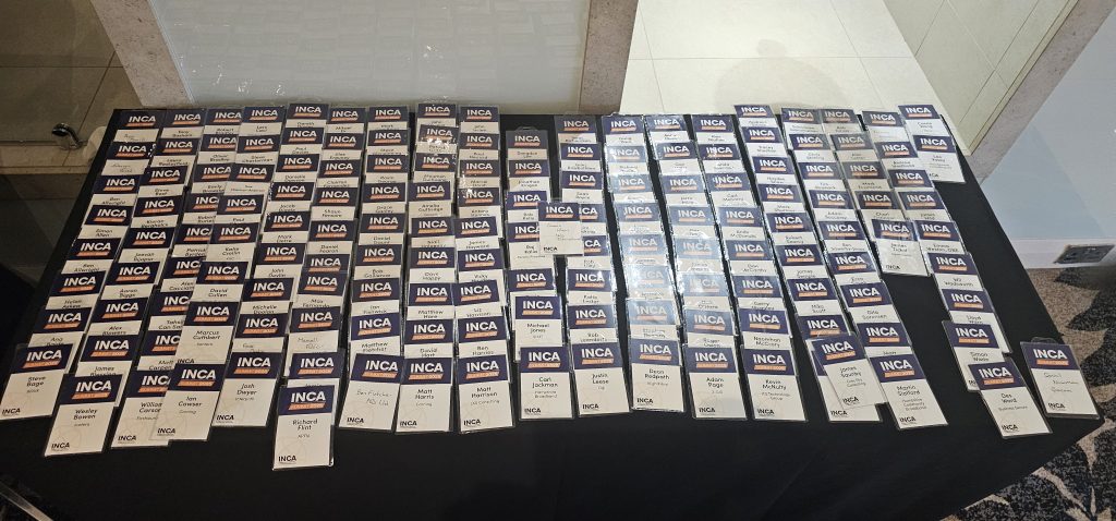 Delegate badges at INCA Summit 2025 registration